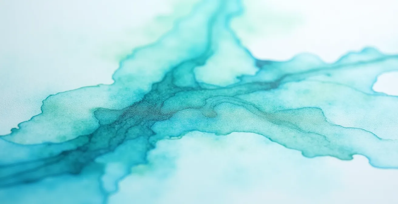 Makroaufnahme von transparenten blauen und grünen Aquarellfarben, die auf Papierfasern verlaufen und ein Gefühl von Leichtigkeit und Raum schaffen.